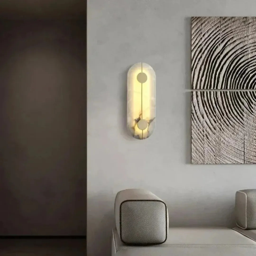 Arandela instalada em parede cinza ao lado de quadro decorativo em sala de estar elegante, com poltrona ao fundo — Arandela de parede mármore nórdica cobre luxo Alara — Tonzi