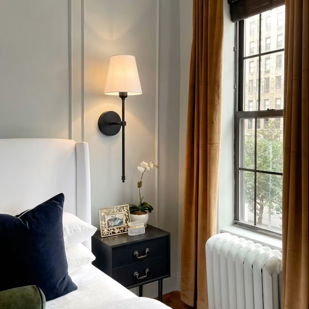 Arandela de parede metal em em preto fosco e abajur tecido no quarto perto da janela