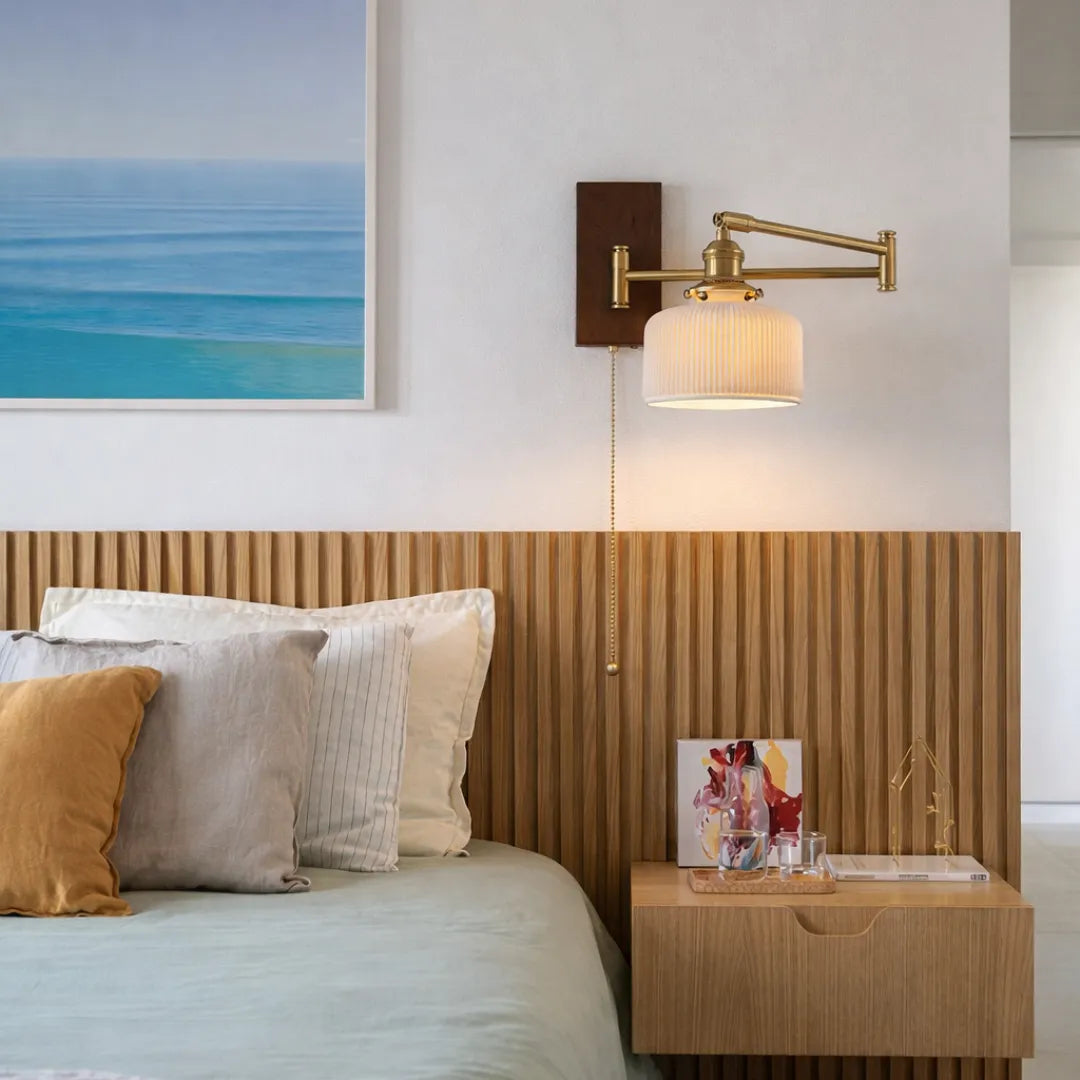 Arandela Eiden acesa sobre cabeceira de cama ripada em madeira em quarto aconchegante com almofadas neutras e quadro decorativo — Luminária de parede madeira LED braço giratório Eiden — Tonzi