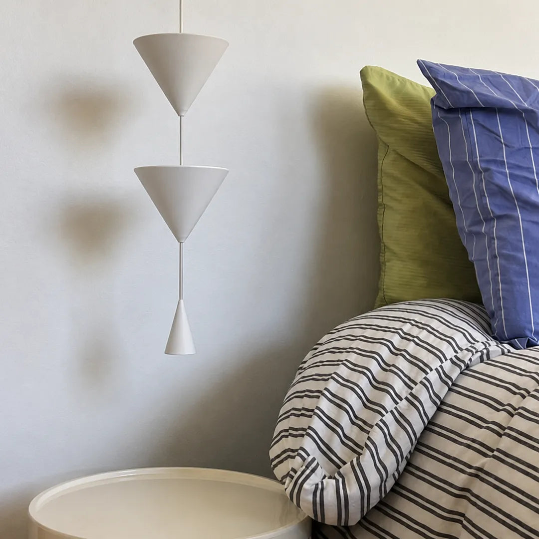 Pendente em metal branco em close sobre cabeceira de quarto com almofadas verdes, azul e listrada — Luminária pendente metal LED cônica nórdica Pino — Tonzi