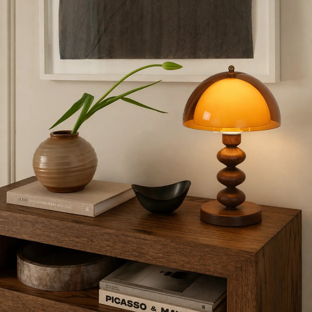 Luminária cogumelo acesa sobre console de madeira escura ao lado de vaso cerâmico com folha verde, parede neutra com quadro emoldurado ao fundo — Luminária de Mesa Cogumelo Acrílico LED Wabi Sabi Retrô — Tonzi