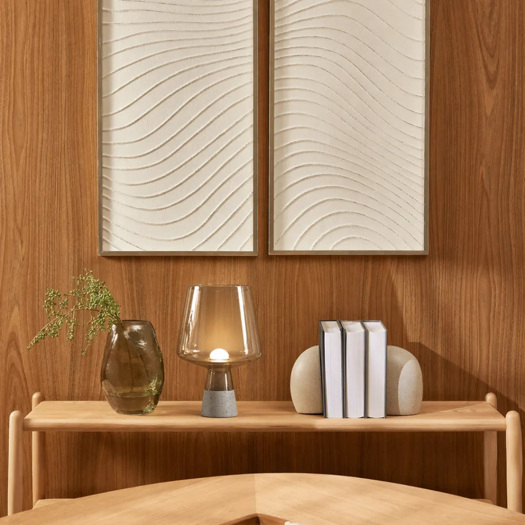 Luminária de mesa em vidro âmbar acesa em console de madeira ao lado de vaso de vidro com galho seco e segurador de livros, painel de madeira esculpido ao fundo — Luminária de Mesa Moderna Vidro Base Mármore — Tonzi