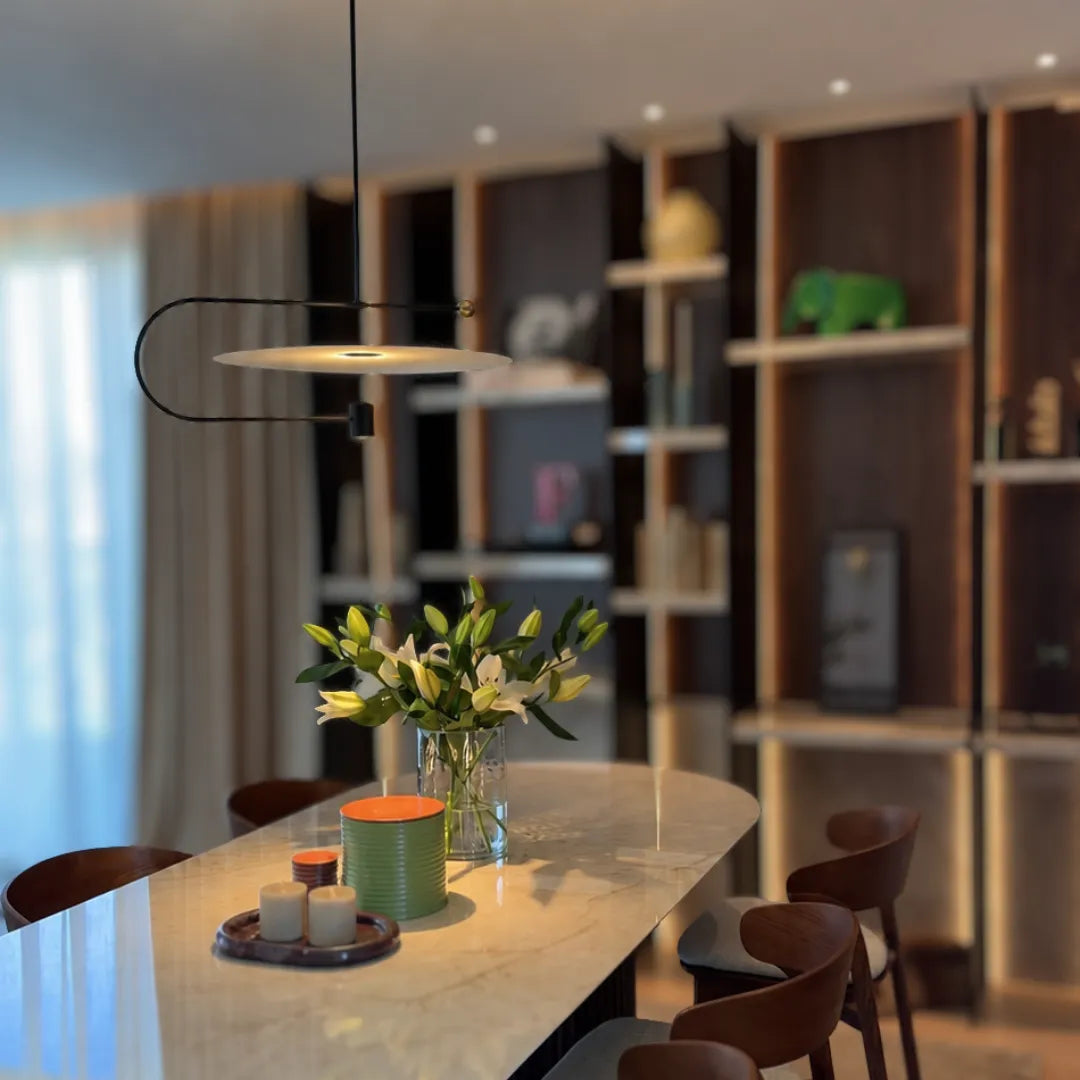 Pendente disco preto iluminando mesa de jantar de mármore com arranjo de lírios e estante amadeirada — Luminária Pendente Disco Metal LED Minimalista Eclipse — Tonzi