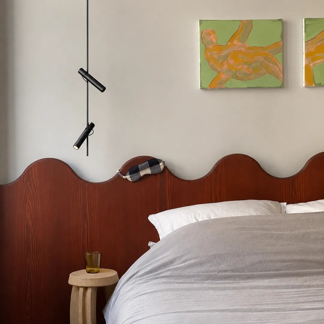 Pendente preto com spots rotativos sobre cabeceira ondulada de madeira escarlate em quarto com parede neutra e quadros figurativos — Luminária pendente metal LED rotativa moderna Orbi — Tonzi