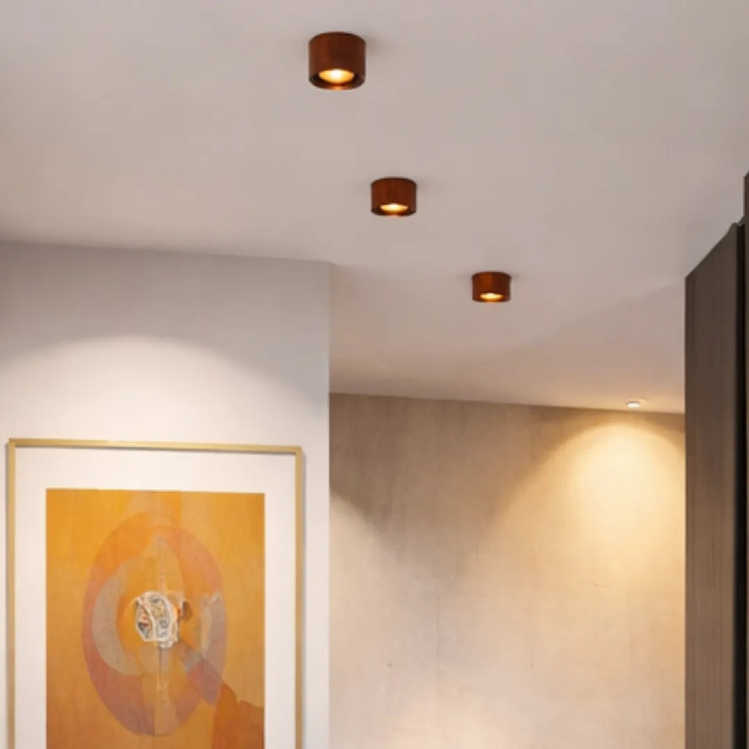 Três plafons no teto de corredor com luz acesa e quadros na parede — Luminária Plafon LED ultrafino rotativo Nivor — Tonzi